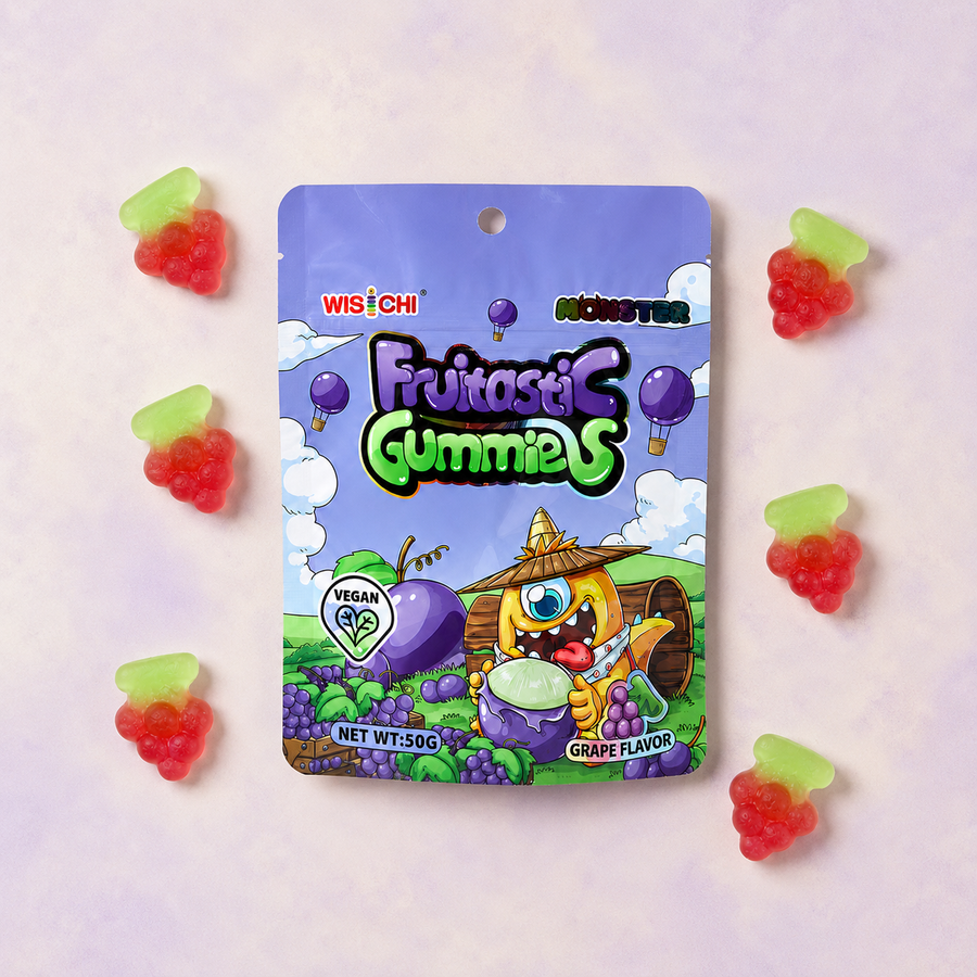 A package of Wischi Fruitase Gummies grape flavor is displayed on a light pink background, surrounded by six individual gummy candies shaped like red raspberries with light green tops.
