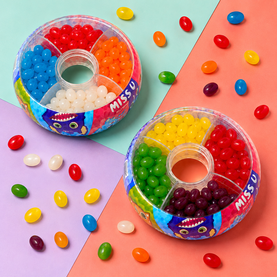 Two round plastic candy bins filled with assorted jelly beans, arranged on a pastel geometric background with scattered jelly beans around them. The brand name MISS U is visible on the bin rims.