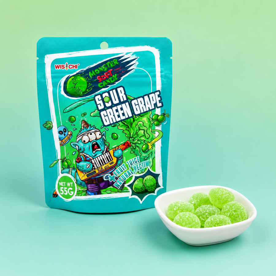 A stand-up pouch of Wisfetti Monster Soda Sour Green Grape candy is shown next to a small white bowl filled with round, translucent green candies on a light mint-green background.